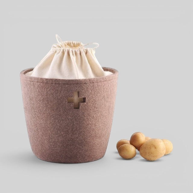 Baabuk large brown felted wool basket with a Swiss cross cutout and cream drawstring liner, holding potatoes.