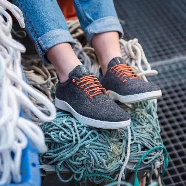 Baabuk Classic Wooler sneakers in grey wool with bright orange laces and a white TPU sole worn with blue jeans.