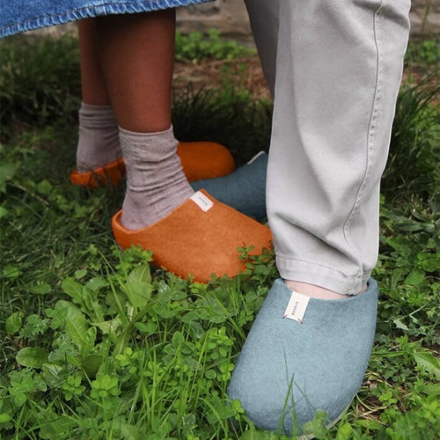Baabuk Corkybuk slippers in light grey and orange felted wool worn on grass by two people