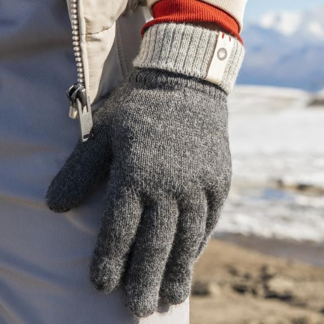 Baabuk dark grey baby alpaca wool gloves worn outdoors with a ribbed cuff in a snowy mountain setting