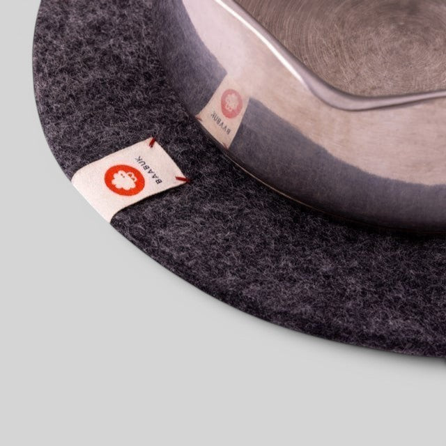 Baabuk dark grey felted wool trivet hot plate with a small leather brand tag under a metal pot