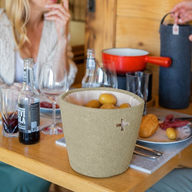 Baabuk khaki felted wool basket with leather strap on a dining table, perfect for serving bread or fruit.
