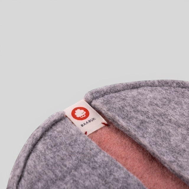 Baabuk pink and grey felted wool potholder with a branded fabric tag, designed for heat-resistant kitchen use.