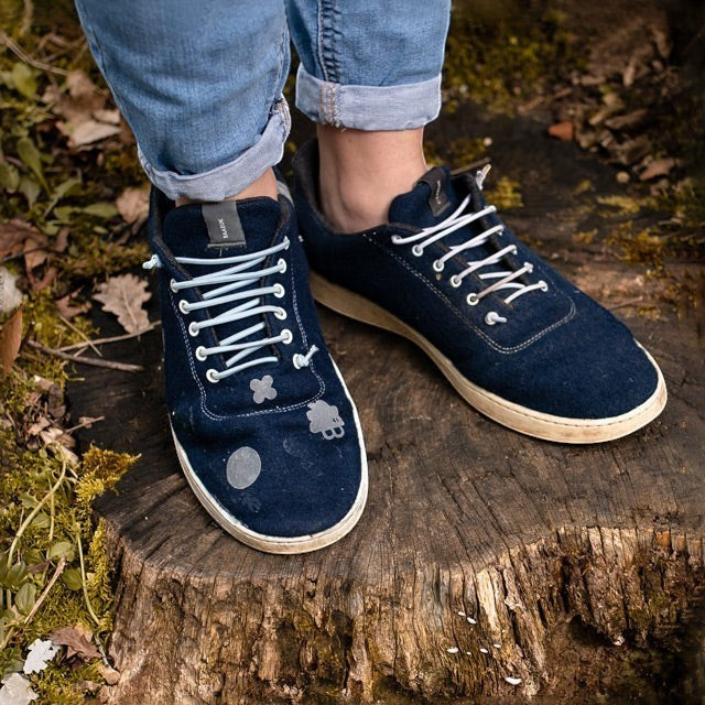 Baabuk wool sneakers featuring a repair kit with adhesive patches applied to the dark blue fabric surface.